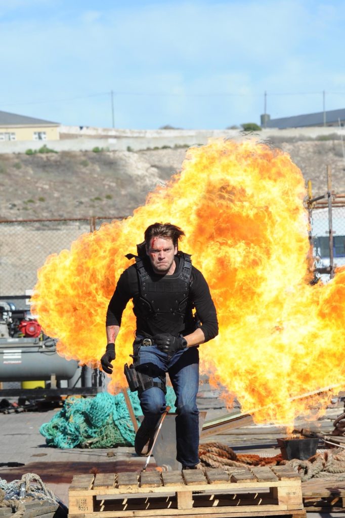 Mason Pollard (played by Dominic Sherwood) runs from a massive explosion.